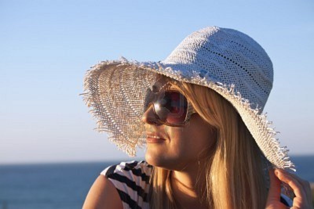 Женщина в соломенной шляпе и очках на берегу моря крупным планом