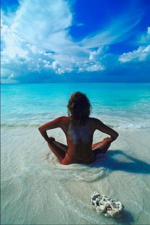 Женщина сидит на красивом пляже в приливе воды
